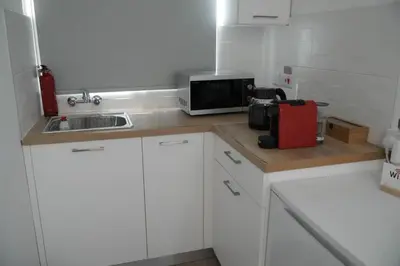 a small kitchen with white cabinets and a microwave at Athalassas corner in Strovolos