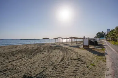 an empty beach with umbrellas and the water at Armonia Seafront Studio in Limassol