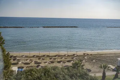 a beach with a bunch of umbrellas and the ocean at Armonia Seafront Studio in Limassol