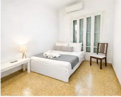 a white bedroom with a bed and a chair at Cozy Corner 2 Bdr Nicosia Center Platform 357 Ltd in Nicosia