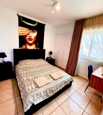 a bedroom with a bed with a large painting on the wall at Carisa rooms for holiday in Larnaka