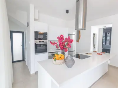 a white kitchen with a vase of flowers on a counter at Holiday Home Protaras Aqua Pearl Villa AQ01 by Interhome in Protaras