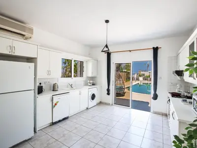 a kitchen with white cabinets and a view of a pool at Holiday Home Protaras Villa mit Pool am Strand der Fig Tree Bay by Interhome in Protaras