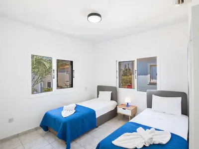 two beds in a room with two windows at Holiday Home Protaras Villa mit Pool am Strand der Fig Tree Bay by Interhome in Protaras