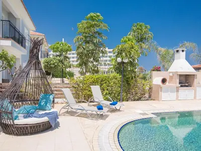 a pool with chairs and a hammock next to a building at Holiday Home Protaras Villa mit Pool am Strand der Fig Tree Bay by Interhome in Protaras