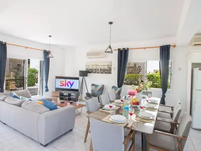 a living room with a table and a tv at Holiday Home Protaras Villa mit Pool am Strand der Fig Tree Bay by Interhome in Protaras