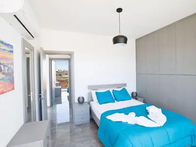 a bedroom with a large bed with blue pillows at Holiday Home Protaras Olivine Villa mit Pool und einem Dachgarten by Interhome in Protaras