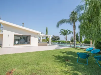 a yard with two chairs and a swimming pool at Holiday Home 4-Schlafzimmer-Villa mit Pool im Zentrum von Protaras by Interhome in Protaras