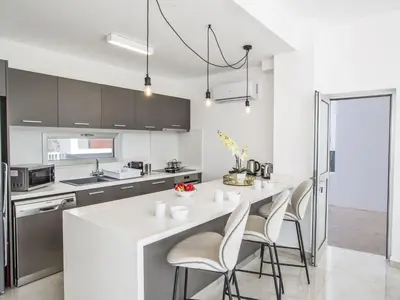 a kitchen with a white counter and some chairs at Holiday Home 3-Schlafzimmer-Villa mit privatem Pool im Zentrum by Interhome in Protaras