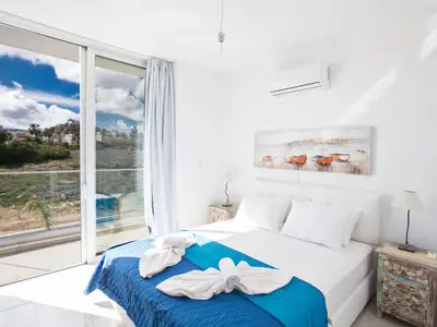 a white bedroom with a bed and a large window at Holiday Home 3-Schlafzimmer-Villa mit privatem Pool im Zentrum by Interhome in Protaras
