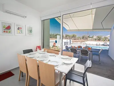 a dining room with a table and chairs and a pool at Holiday Home Wunderschöne- geräumige Ferienvilla mit BBQ by Interhome in Protaras