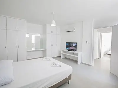 a white bedroom with a bed and a tv at Holiday Home Wunderschöne- geräumige Ferienvilla mit BBQ by Interhome in Protaras