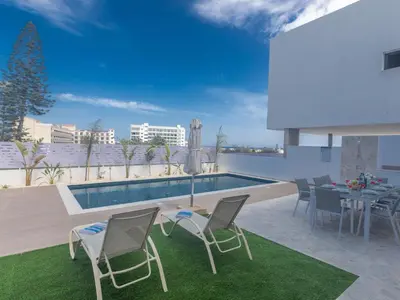 a patio with a table and chairs and a pool at Holiday Home Protaras Aqua Pearl Villa AQ05 by Interhome in Protaras