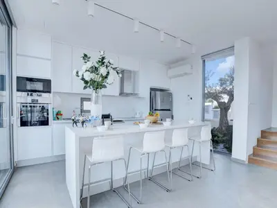 a white kitchen with a white counter and stools at Holiday Home Protaras Ferienvilla mit privatem Pool- Whirlpool by Interhome in Paralimni