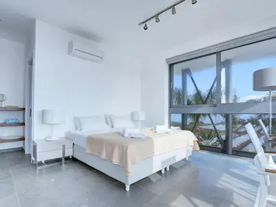 a white bedroom with two beds and a large window at Holiday Home Protaras Ferienvilla mit privatem Pool- Whirlpool by Interhome in Paralimni