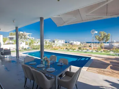 a dining room with a table and a pool at Holiday Home Ferienvilla Olivine Pearl mit Meerblick by Interhome in Protaras