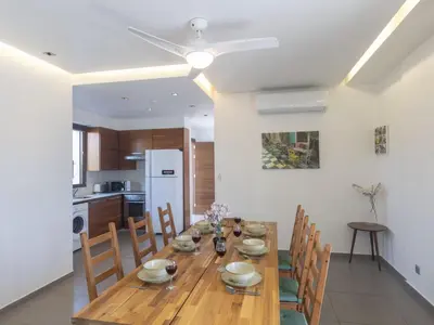 a kitchen and dining room with a wooden table and chairs at Holiday Home Ayia Napa Satin Villa SVI1 by Interhome in Ayia Napa