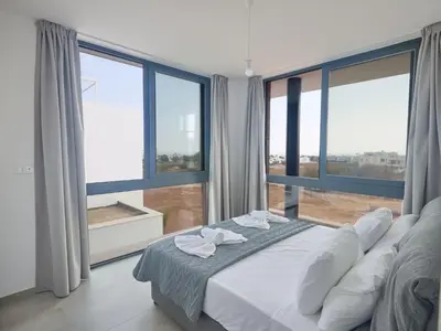 a bedroom with a large bed and large windows at Holiday Home Protaras Aqua Pearl Villa AQ11 im Zentrum by Interhome in Protaras