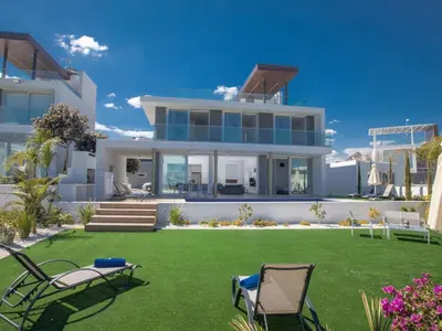 a house with a lawn and chairs in the yard at Holiday Home Schöne Villa Olivine Pearl OL5 mit Garten by Interhome in Protaras