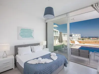 a bedroom with a bed and a balcony with a pool at Holiday Home Schöne Villa Olivine Pearl OL5 mit Garten by Interhome in Protaras