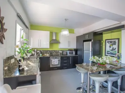 a kitchen with white and green walls and a island with bar stools at Holiday Home Charmante 3-Schlafzimmer-Villa DI12 mit privatem Pool by Interhome in Protaras