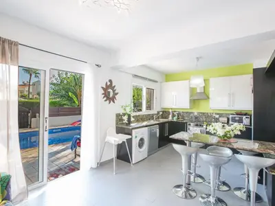 a kitchen with white cabinets and bar stools at Holiday Home Charmante 3-Schlafzimmer-Villa DI12 mit privatem Pool by Interhome in Protaras