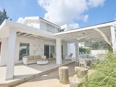 a white house with a patio with a couch and a table at Holiday Home Protaras Serifos Villa SV7 100m vom Strand entfernt by Interhome in Paralimni