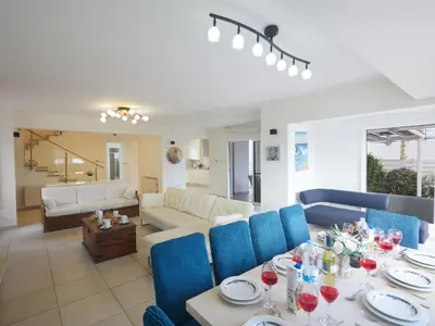 a living room with a table and blue chairs at Holiday Home Protaras Serifos Villa SV7 100m vom Strand entfernt by Interhome in Paralimni