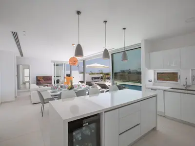 a kitchen and living room with white cabinets and a fireplace at Holiday Home Haus in Pernera mit Bi-Fold Patio by Interhome in Protaras