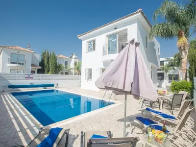 a pool with an umbrella and chairs next to a house at Holiday Home Ferienvilla PV17 mit Sonnenterrasse und Pool by Interhome in Protaras