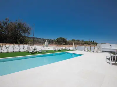 a swimming pool with lawn chairs and umbrellas at Holiday Home Geräumige Villa mit großem Garten und Pool by Interhome in Protaras