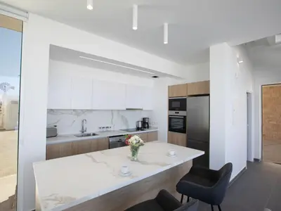 a white kitchen with a table and two chairs at Holiday Home Ferienvilla Vie Bleu mit großem Pool by Interhome in Protaras