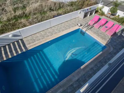 a dolphin swimming in a swimming pool with two chairs at Holiday Home Protaras Perle Villa PE16 by Interhome in Protaras