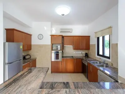 a kitchen with wooden cabinets and a stainless steel refrigerator at Holiday Home Protaras Ferienvilla AV6 by Interhome in Protaras