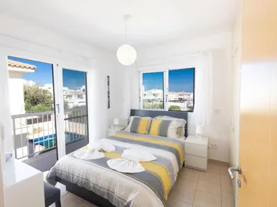 a bedroom with a bed and a balcony with windows at Holiday Home Protaras Blauer Fluss Villa BR26 by Interhome in Protaras