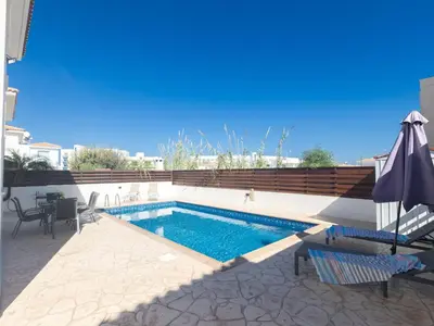 a swimming pool with chairs and a table and an umbrella at Holiday Home Protaras Blauer Fluss Villa BR26 by Interhome in Protaras