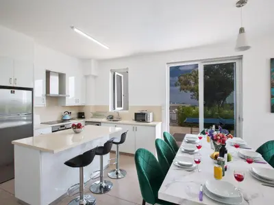 a kitchen with a table with green chairs at Holiday Home Schöne- topmoderne Ferienvilla auf Zypern by Interhome in Protaras