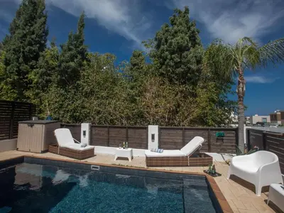 a swimming pool with white furniture and a swimming pool at Holiday Home Protaras Menelaos Villa MV7 by Interhome in Paralimni