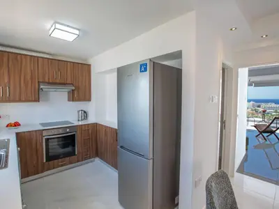 a kitchen with wooden cabinets and a refrigerator at Apartment Schöne Wohnung in Ayia Napa mit Garten by Interhome in Ayia Napa