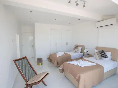 a white room with two beds and a chair at Apartment Schöne Wohnung in Ayia Napa mit Garten by Interhome in Ayia Napa