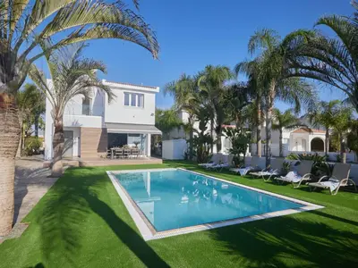 a swimming pool in front of a house with palm trees at Holiday Home Moderne- geräumige Ferienvilla by Interhome in Ayia Napa