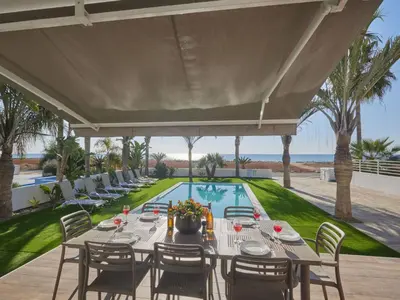 an outdoor dining area with a table and chairs and a pool at Holiday Home Moderne- geräumige Ferienvilla by Interhome in Ayia Napa