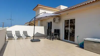 a patio with chairs and an umbrella on a house at Penthouse Apartment - Sleeps 4 - Sea Views in Paralimni