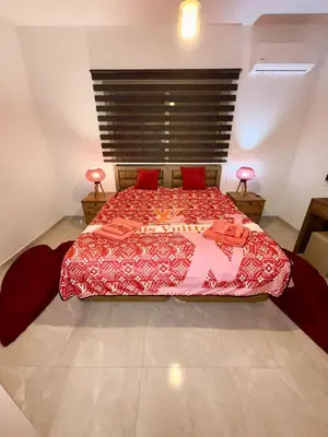 a bedroom with a large bed with red sheets and two lamps at Lapta Red 1 bedroom apartment
