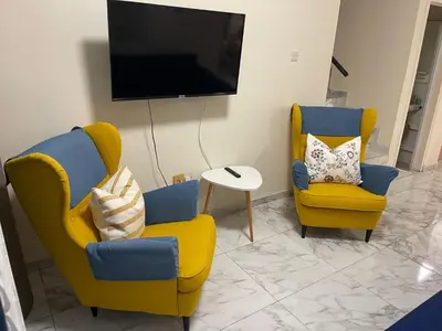 a living room with two chairs and a tv at Sea view maisonette on coastal road, Zygi in Zygi