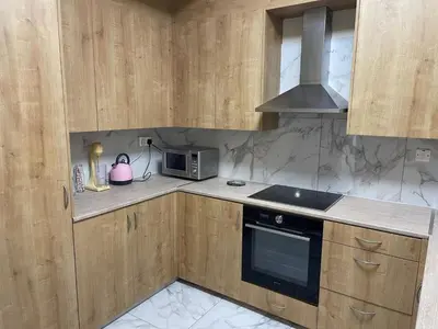 a kitchen with wooden cabinets and a sink and a microwave at Sea view maisonette on coastal road, Zygi in Zygi