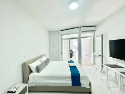 a bedroom with a bed and a desk and a television at Silver Blu APT - Beachside - Location - Office in Limassol