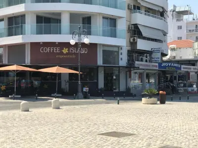 a city square with a coffee stand in front of buildings at Queen victoria sea view apartments in Larnaka