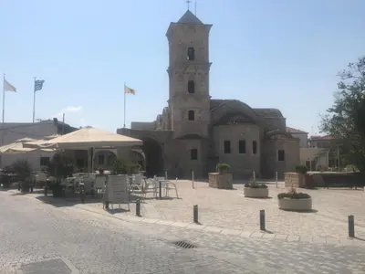 a building with a clock tower and tables and chairs at Queen victoria sea view apartments in Larnaka