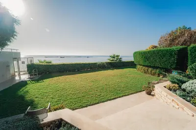a garden with a lawn and the ocean in the background at Beach Front View Apartment Sea Pool & Prime Location in Limassol
